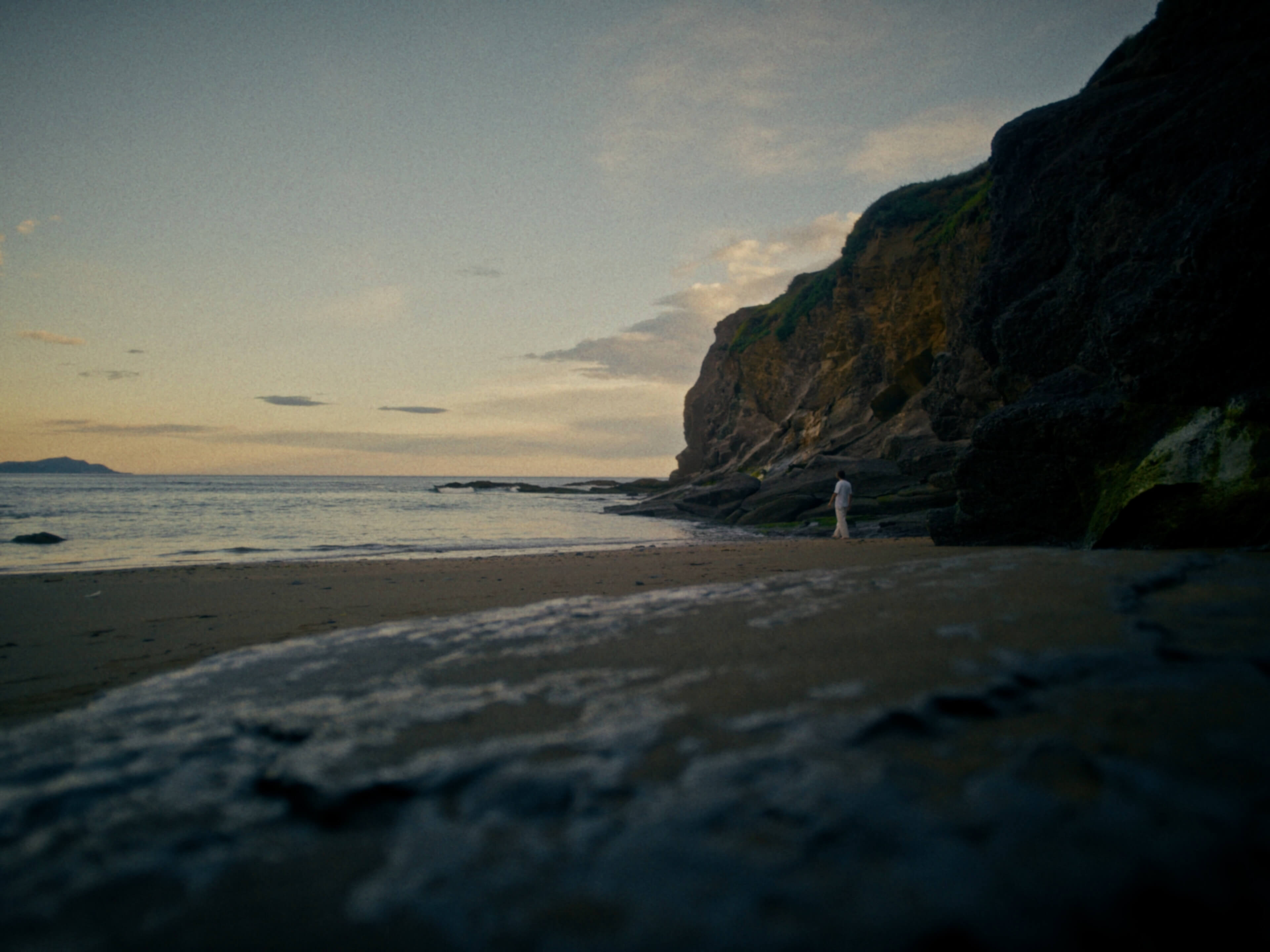 Un homme marche sur une plage avec des falaises
